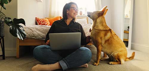 Woman on couch with pet and laptop
