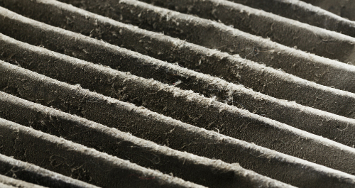 Close-up photo of a dirty air filter covered in dust 