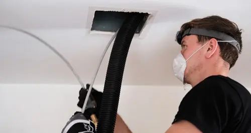 A man cleaning an air duct