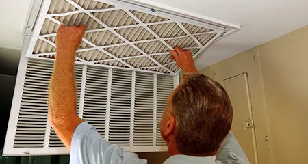 Man changing air filter on ceiling