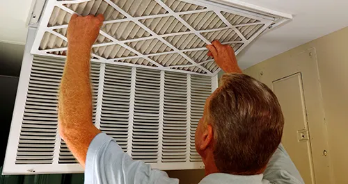 Man changing air filter on ceiling