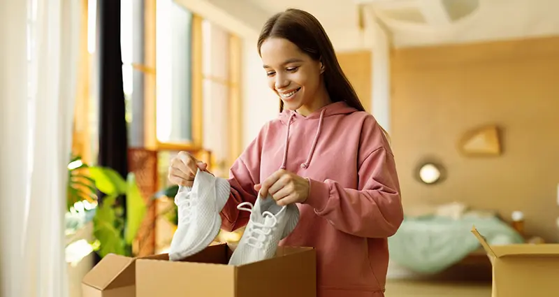 Girl packing her sneakers into a box