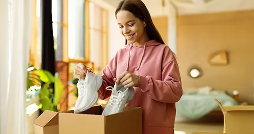 Girl packing her sneakers into a box