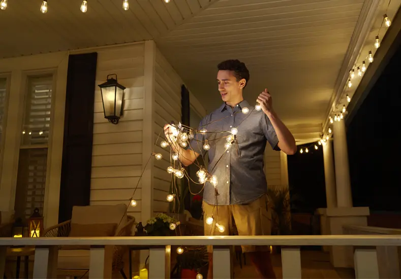 man hanging lights on porch