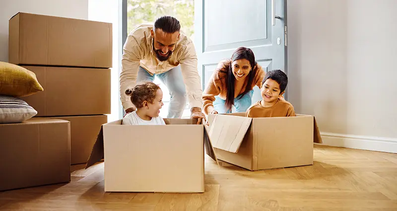 Children riding moving boxes into new home