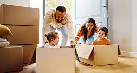Children riding moving boxes into new home
