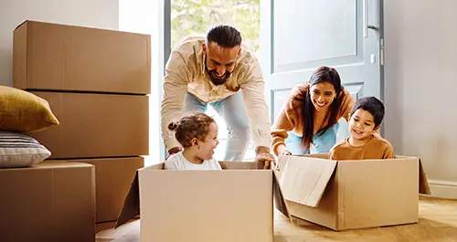 Children riding moving boxes into new home