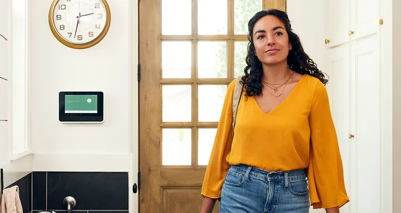 Woman entering home with Vivint hub on wall