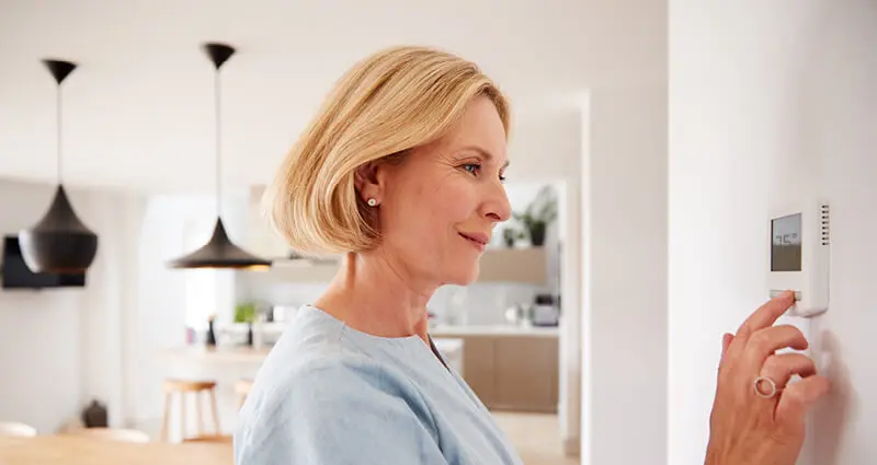 Woman sitting on couch pointing remote control at AC
