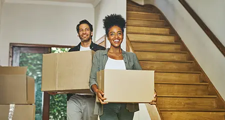 Happy couple carrying moving boxes