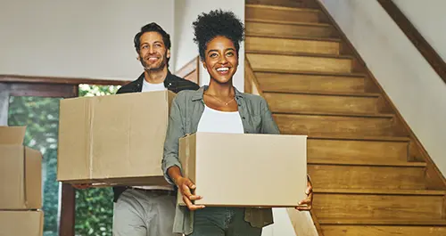 Happy couple carrying moving boxes