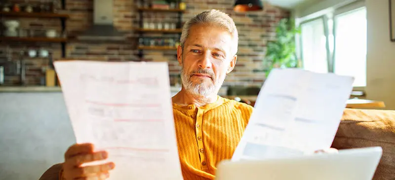 Man reviewing utility bills on the couch