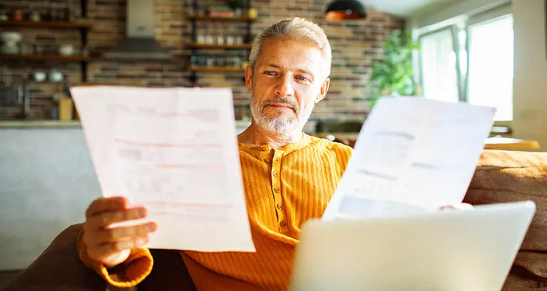 Man reviewing utility bills on the couch