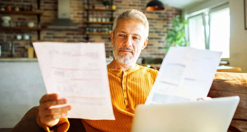 Man reviewing utility bills on the couch