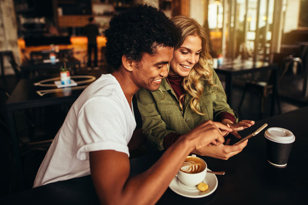 Friends-sharing-referrals-on-smarthpone-while-drinking-coffee