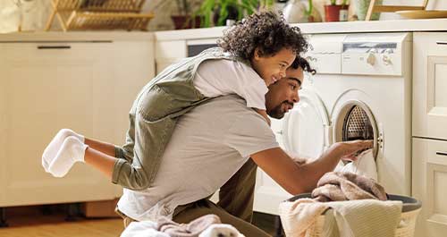 Dad taking laundry out and kid playing on his back