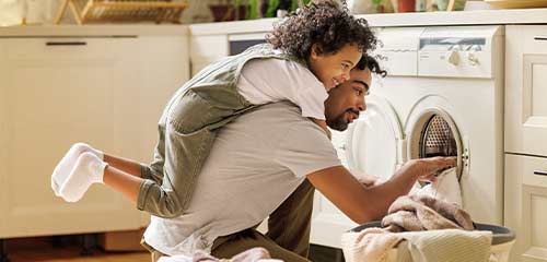 Dad taking laundry out and kid playing on his back
