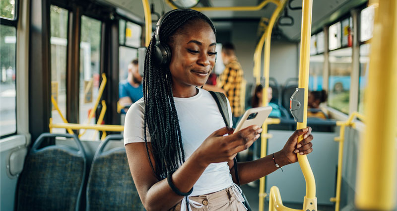 Young black woman on bus looking at smartphone