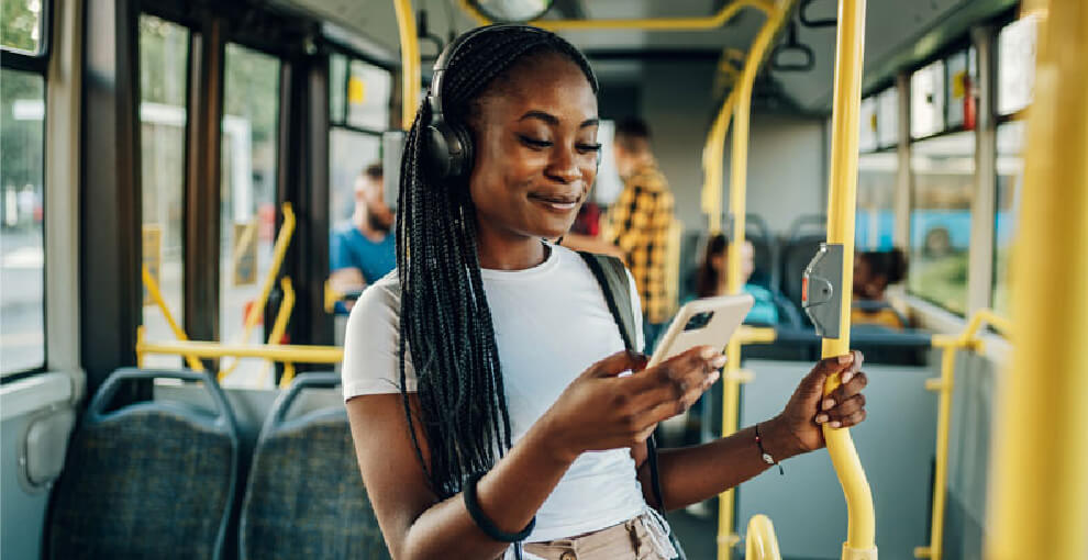 Young black woman on bus looking at smartphone