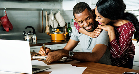 Happy couple paying bills at kitchen table