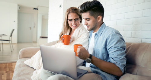 Happy couple on the couch looking at a laptop