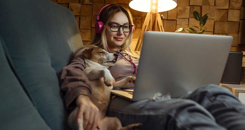 Woman on couch with pet and laptop
