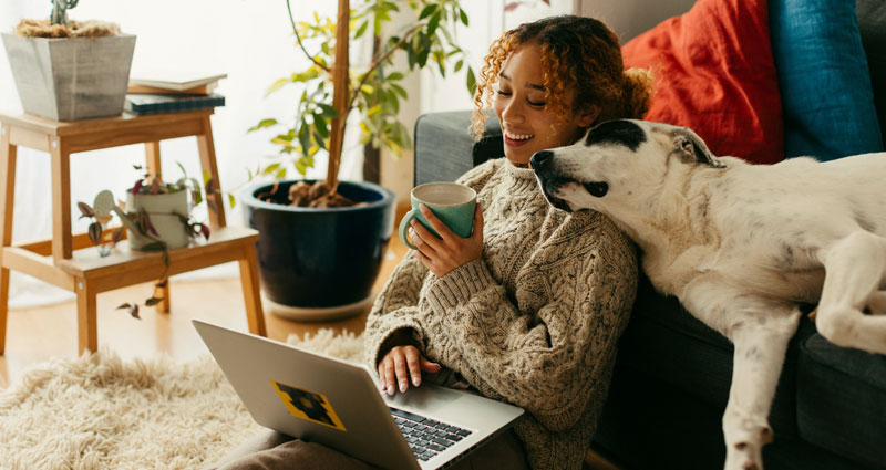 Photograph of a woman and her cat sitting in front of a portable electric heater 