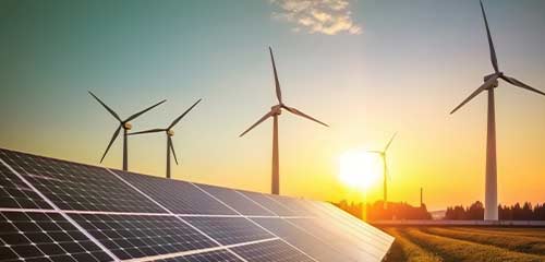 House rooftop with solar panels and wind turbines in the background