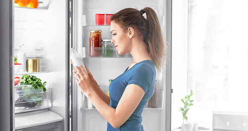 Woman taking food out of refrigerator at home