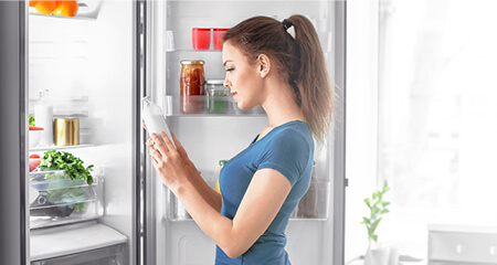 Woman taking food out of refrigerator at home