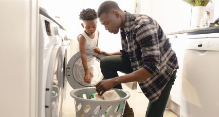 Father and son washing clothes in washing machine