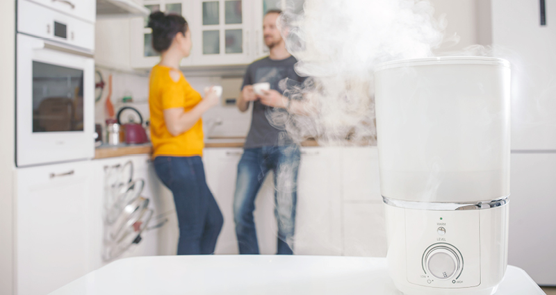 Couple standing in background while humidifier runs on the kitchen counter