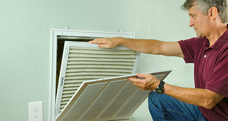 Photo of a man changing his indoor air conditioner's filter