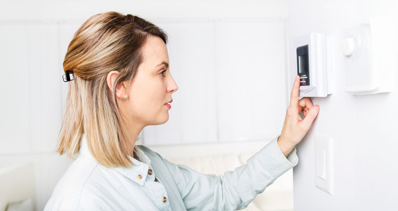 Woman setting thermostat at home