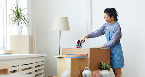 Young woman packing boxes for her new apartment