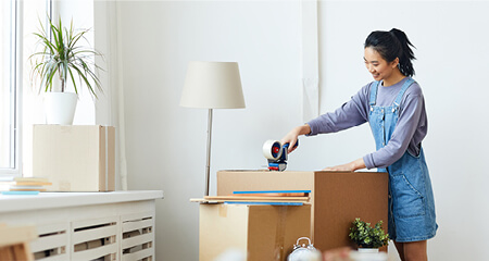 Young woman packing boxes for her new apartment