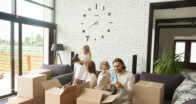 Kids unpacking boxes with their parents in modern living room