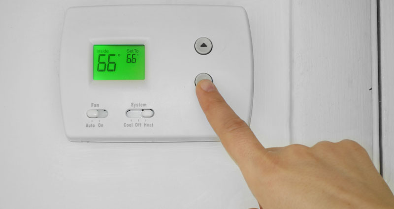 hand sets thermostat to 66
