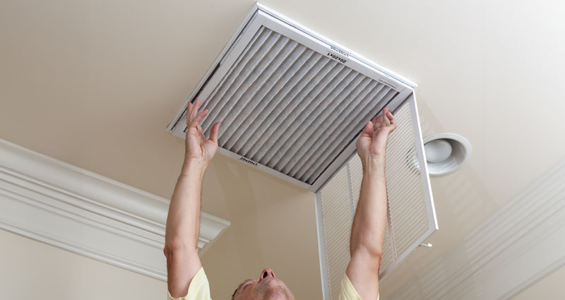 man changing AC filter on ceiling