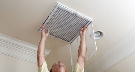 man changing AC filter on ceiling