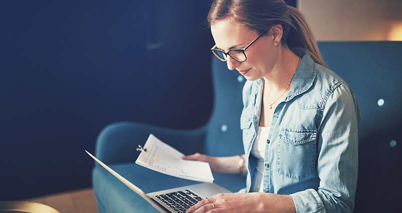 Woman with her laptop viewing bills and paperwork