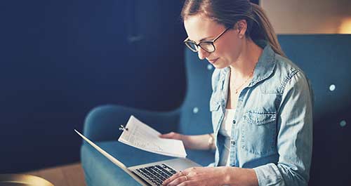 Woman with her laptop viewing bills and paperwork
