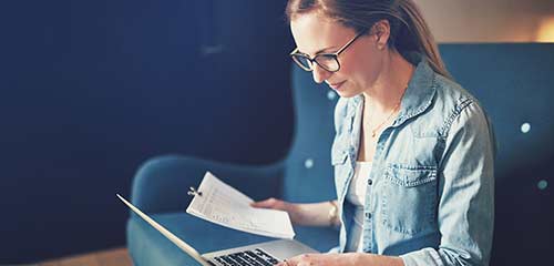 Woman with her laptop viewing bills and paperwork