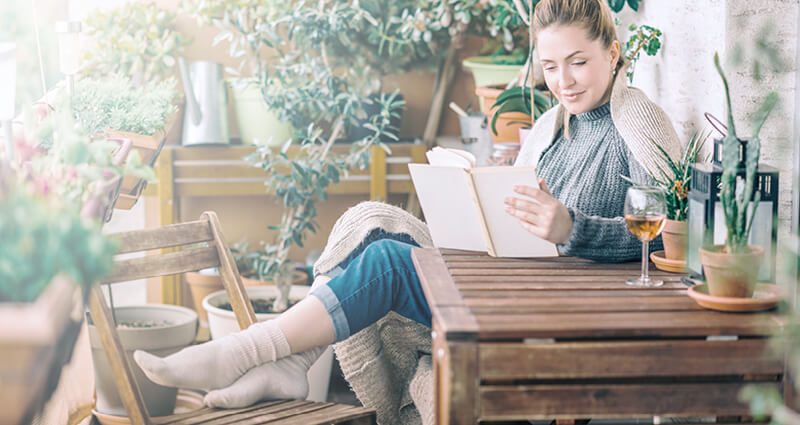 Beautiful woman relaxing and reading a book on balcony