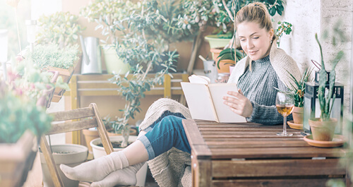 Beautiful woman relaxing and reading a book on balcony