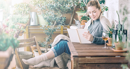 Beautiful woman relaxing and reading a book on balcony