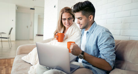 Couple looking at laptop while drinking coffee