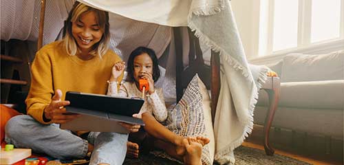 Mother and daughter playing with tablet at home
