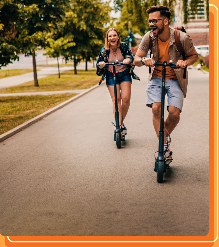 Happy friends riding electric scooters in the city