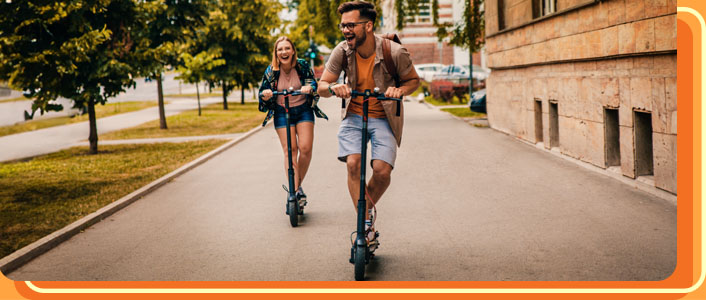 Happy friends riding electric scooters in the city